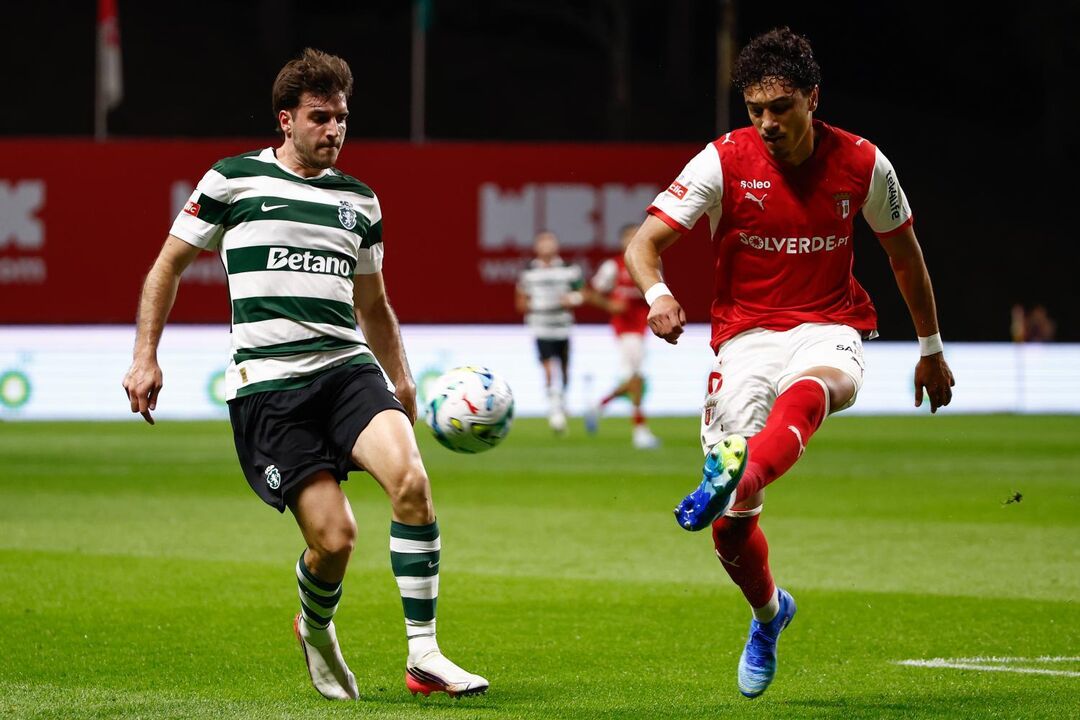 Os jogadores disputam a posse da bola no relvado no