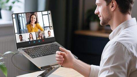 Um homem está numa videochamada com outras pessoas através de um portátil